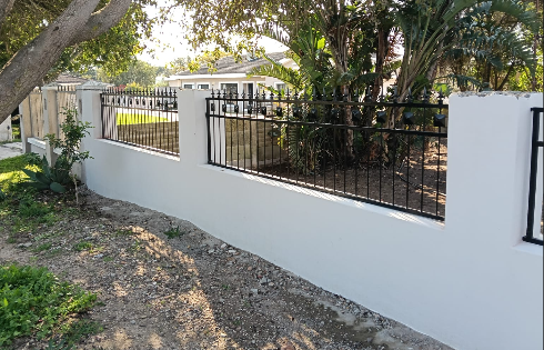 Black steel fence installed along a white boundary wall